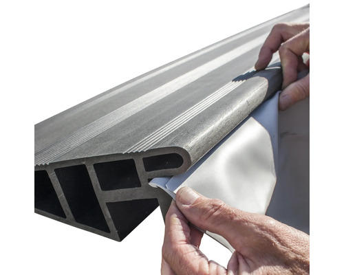 Une personne retire le film protecteur d''un profilé de marche d''escalier