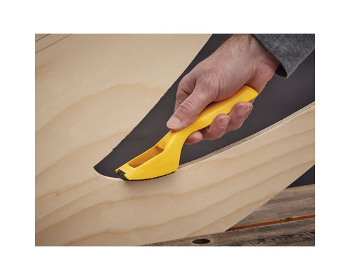 Main avec outil d''ébavurage jaune sur le bord du bois