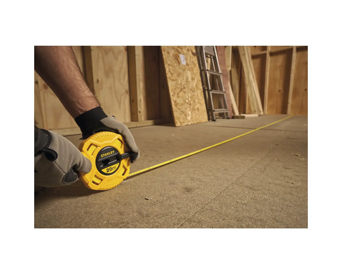 Personne déroulant un mètre ruban jaune Stanley de 20 mètres