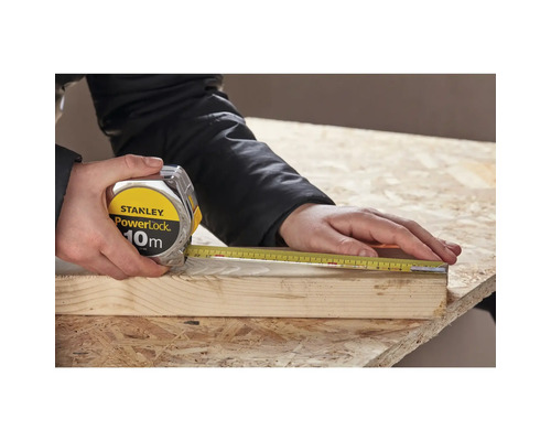 Une personne mesure une pièce de bois avec un mètre à ruban Stanley PowerLock de 10 mètres.