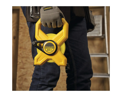 Un homme tient un ruban à mesurer Stanley jaune de 30 mètres