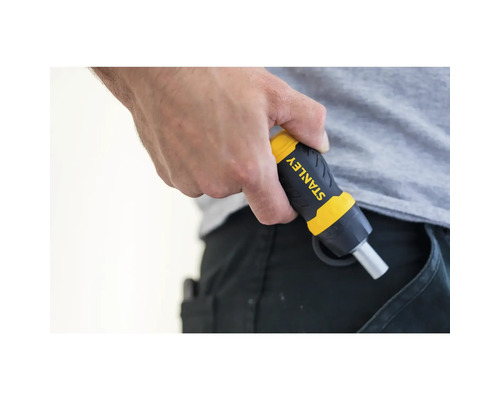 Une personne tient un tournevis de la marque Stanley à la main, l''outil étant rangé dans une poche de pantalon.