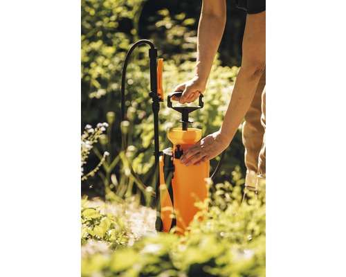 Une personne utilise un pulvérisateur à pression dans le jardin.