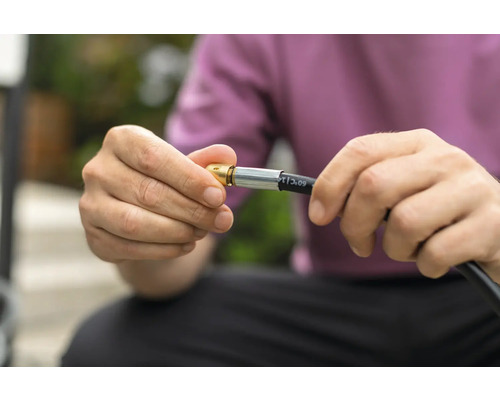 Une personne connecte un tuyau de gaz à un raccord.