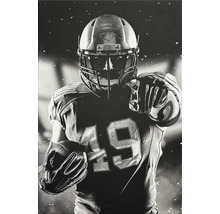 Photographie en noir et blanc d''un joueur de football américain avec casque et ballon
