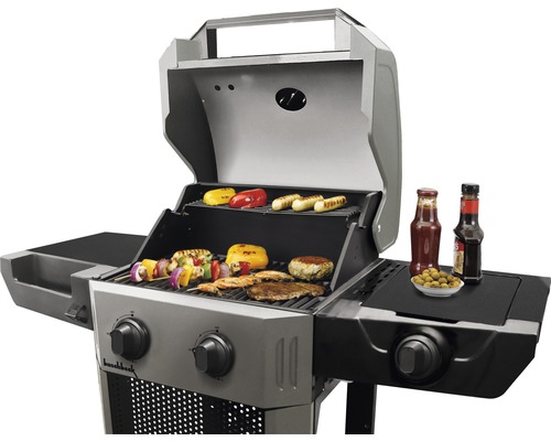 Gasgrill mit Grillgut, Saucen und Beilagen auf Ablageflächen