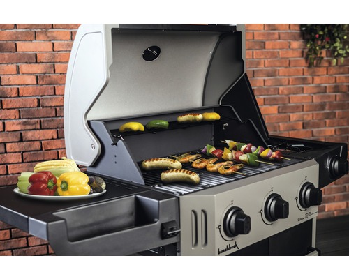 Barbecue à gaz avec des aliments grillés comme des saucisses, des légumes et des brochettes de kebab