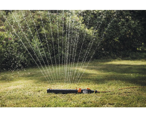 Rasensprenger bewässert Rasenfläche im Garten