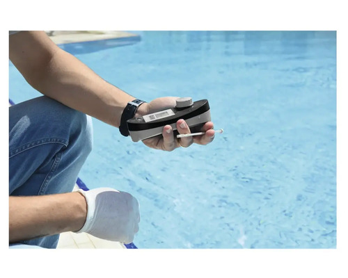 Une personne mesure la qualité de l''eau d''une piscine avec un testeur de piscine.