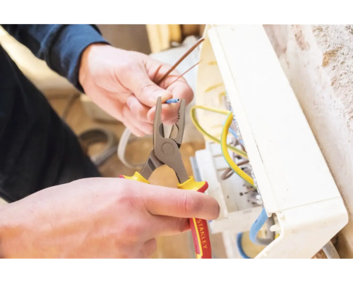 Elektriker arbeitet mit einer Zange an einer elektrischen Anlage