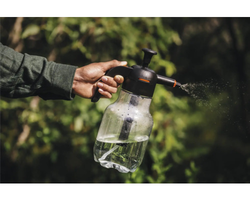 Eine Hand hält eine Drucksprühflasche, aus der Wasser versprüht wird.