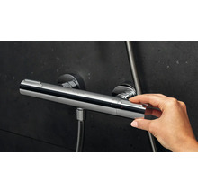 Gros plan d''une main actionnant un mitigeur thermostatique de douche Hansgrohe