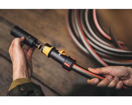 Personne raccordant un tuyau d''arrosage à un raccord de tuyau