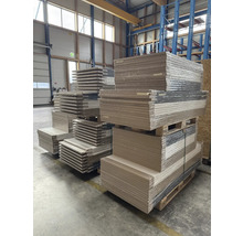 Plaques de bois empilées sur des palettes dans un entrepôt