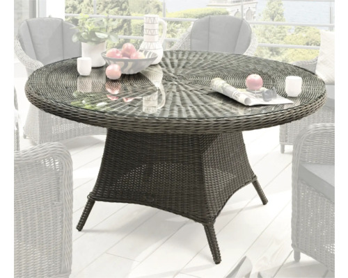 Table de jardin en rotin avec plateau en verre sur une terrasse