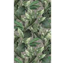 Papier peint avec des feuilles tropicales devant un mur de briques