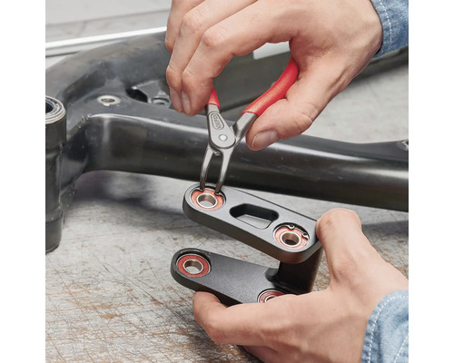 Une personne utilise une pince à circlips pour fixer un circlips sur une pièce de machine.