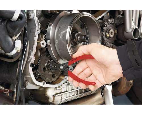Une personne utilise une pince à circlips de Knipex sur un moteur de moto.
