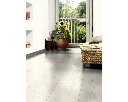 Pièce lumineuse avec plancher en bois, tournesols en pot et tabouret tissé