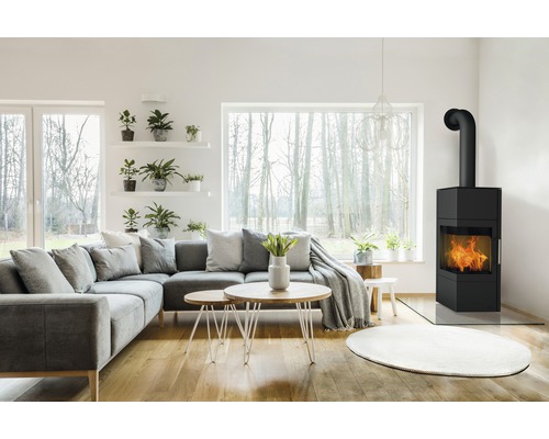 Wohnzimmer mit Ecksofa, Couchtischen und Kaminofen.