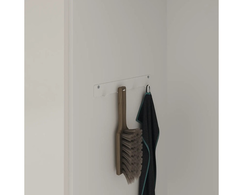Un balai et une serviette sont suspendus au support mural.