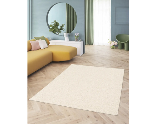 Wohnzimmer mit beigem Teppich, gelbem Sofa und runder Spiegelfläche.