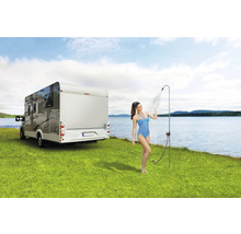 Frau unter Campingdusche neben Wohnmobil auf Rasenfläche an See