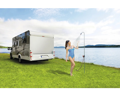 Femme sous douche de camping à côté d''un camping-car sur une pelouse au bord d''un lac