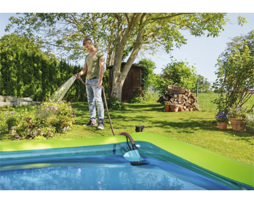 Scène d''un homme remplissant une piscine avec un tuyau d''arrosage.
