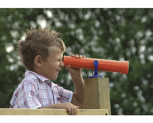 Garçon regardant à travers une longue-vue jouet sur une tour de jeu