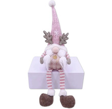 Nain de Noël décoratif avec bonnet, bois de cerf et jambes rayées assis sur une surface blanche