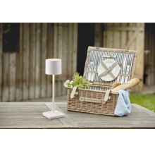 Scène avec une lampe de pique-nique et un panier de pique-nique sur une table en bois à l''extérieur.