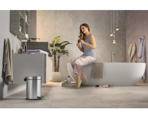 Modernes Badezimmer mit freistehender Badewanne, Waschtisch und Treteimer aus Metall.