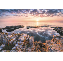 Paysage côtier rocheux au lever du soleil avec des eaux calmes