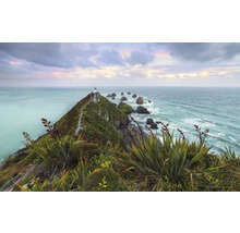 Vue paysagère d'une colline avec un phare au bord de la mer sous un ciel nuageux
