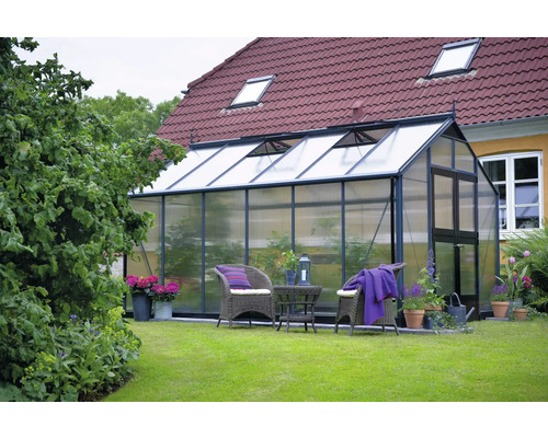 Gewächshaus im Garten mit Gartenmöbeln und Pflanzen