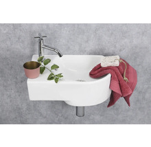 Kleines Waschbecken mit Armatur, Pflanze, Seife und Handtuch vor einer grauen Wand