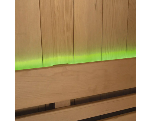 Nahaufnahme einer Saunabank vor einer Holzvertäfelung mit grüner Beleuchtung