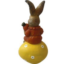 Dekorativer Hase auf einem Osterei mit Karotte in der Hand als Gartendekoration