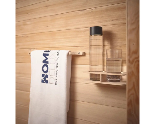 Handtuch an Handtuchhalter, Trinkflasche und Glas auf einem Regal vor einer Holzwand