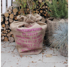 Plante dans un sac de jute imprimé, bois de chauffage à l'arrière-plan