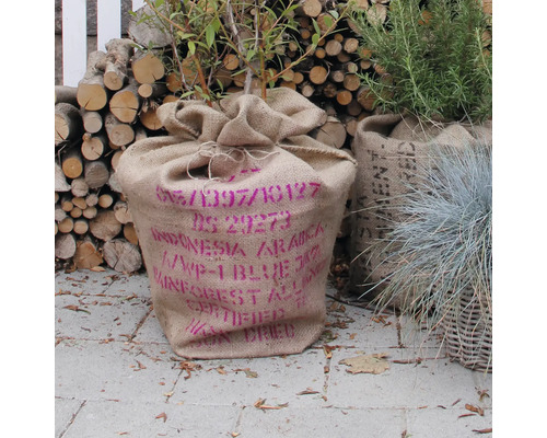 Plante dans un sac de jute imprimé, bois de chauffage à l'arrière-plan