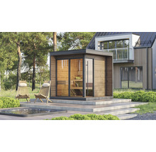 Helle moderne Aussensauna mit Holzfassade und Glaswänden auf einer Terrasse neben einem Pool und Liegestühlen vor einem modernen Haus im Wald.