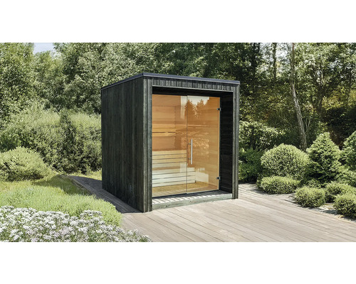 Moderne Gartensauna in Würfelform mit dunkler Holzfassade und großer Glasfront auf einer Holzterrasse im Garten.