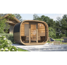 Ovale Fasssauna aus Holz mit Glasfront und schwarzem Schindeldach auf einer Terrasse im Garten.