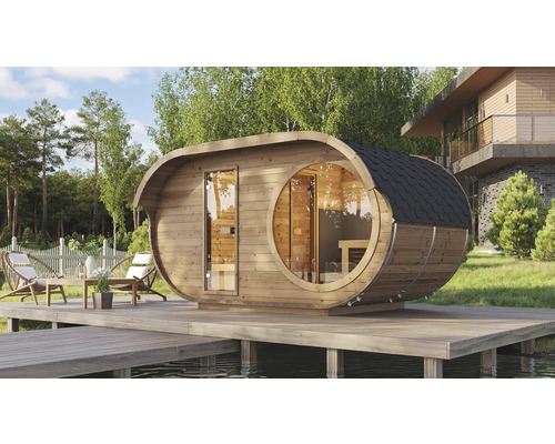 Sauna tonneau ovale moderne en bois avec fenêtre panoramique ronde et porte vitrée sur une terrasse en bois au bord d'un lac.