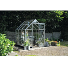 Gewächshaus im Garten mit Pflanzen und Gartenzubehör