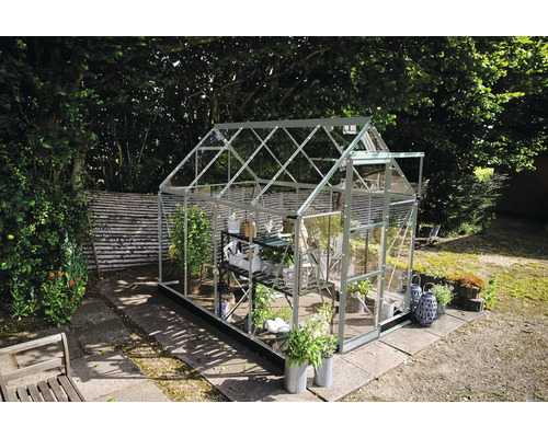 Gewächshaus mit Regalen zur Pflanzenaufzucht im Garten.