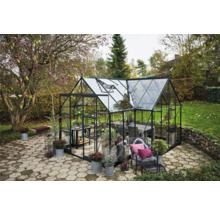 Gewächshaus mit Pflanzen und Möbeln im Garten.