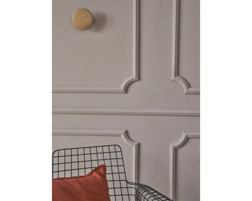 Wand mit Stuckrahmen, Holzhaken und Metallstuhl mit Kissen